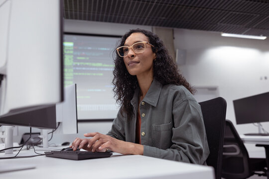 Confident woman coding at a tech workspace setup
