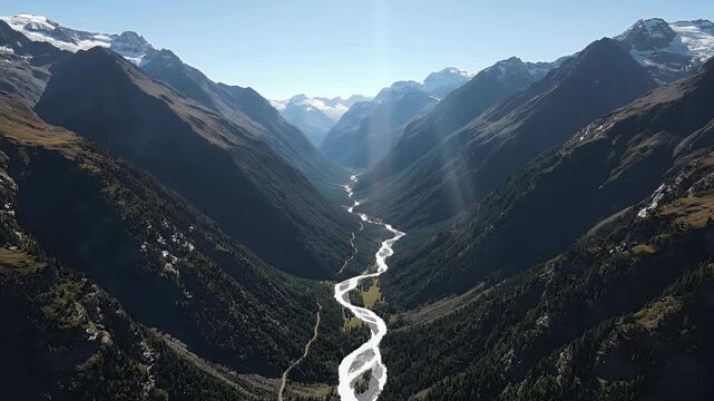 Aerial view of a mountain range with a river winding through the valley. Sunny day with icecaps
