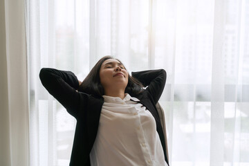 Fototapeta premium Businesswoman relaxed or stretched, leaning back in her office chair, hands clasped behind her head