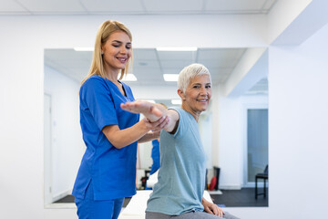 Shoulder pain exercise. Physical therapist helping senior woman with arm mobility in clinic. Healthcare and medicine concept, elderly patient during rehabilitation for muscle and joint problems.