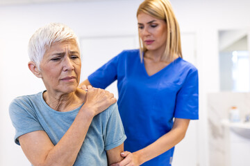 Obraz premium Pain in the shoulder. Upper arm pain, people with body-muscles problem, healthcare and medicine concept. Female physical therapist examining painful shoulder of senior woman in medical clinic.