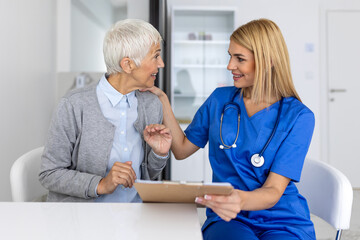 Obraz premium Professional Female Doctor Comforting Senior Patient During Medical Consultation, Practitioner Explaining Healthcare Plan to Elderly Woman in Hospital, Clinical Patient Care and Trust