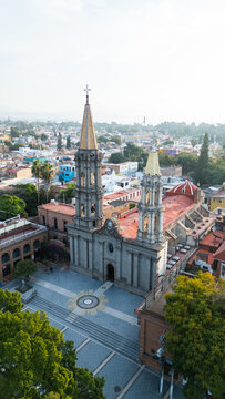 Aerial view of the iconic Parroquia de San Francisco de Asis church, its golden spires piercing the sky above the town, a blend of history and vibrant Mexican life, Chapala, Jalisco, Mexico.