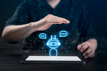 Fototapeta premium Businessman with hands over a glowing AI chatbot icon on a digital tablet. Concept of artificial intelligence assistant, automated customer service, smart communication, and future work technology.