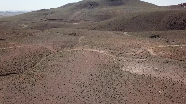 Aerial view of dry rolling hills with sparse vegetation in Ouarzazate. The vast arid landscape highlights desertification patterns in southern Morocco.