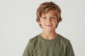 Confident studio headshot of a smiling young preteen boy with bright blue eyes wearing a casual olive green t-shirt against a clean white backdrop.