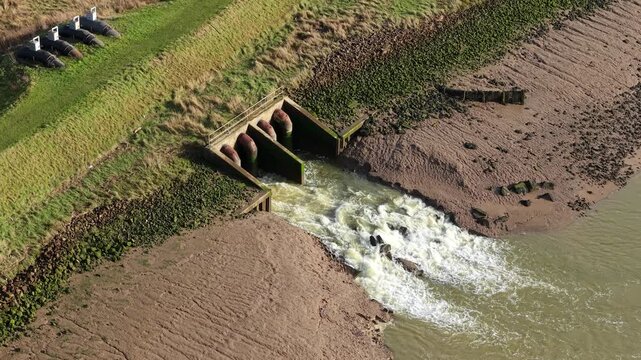 Close Up Aerial View of Massive Outfall Pipes Discharging Water into River Haven from Hobhole Pumping Station in Lincolnshire UK 4K Drone