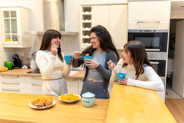 Friends enjoying breakfast, eating and laughing in kitchen