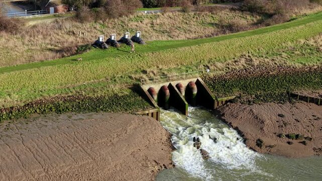 Cinematic aerial of Hobhole pumping station infrastructure in Winter sunlight managing water levels to protect Lincolnshire housing and fertile farms