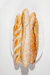 Freshly baked assorted baguettes with golden crust arranged on a white plate under soft natural light