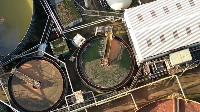 Top down aerial drone view of bubbling activated sludge in industrial vats at a UK wastewater treatment plant for environmental waste management.