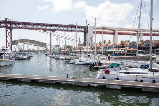 Lisbon, Portugal - june 13 2025: Sailboats docked at Doca de Santo Amaro, beneath the 25 de Abril, where locals and tourists enjoy waterfront dining, leisure, and maritime views.