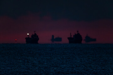 朝焼けの白む空と暗い海の間の水平線に浮かぶ船影たち20220101
