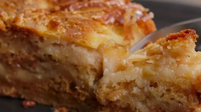 fork cuts off a small piece of delicious crumbly pie on a plate. The dry dough breaks easily. Close up shot of eating a sweet dessert.