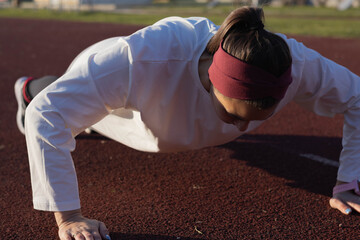 A woman focuses on deep push-ups in an outdoor setting, showcasing strength and dedication