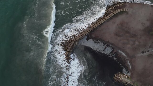 Aerial Drone View of Waves Crashing on a Curved Breakwater in Porto Pino, Sardinia, Italy