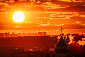 Obraz premium Golden light bathes the skyline as the sun sets, casting a warm glow on the church dome and clouds