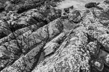 The image is of a rocky shoreline with a large rock formation