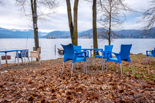 Chairs of a summer bar along the shoreline of Orta Lake, during wintertime. Is a glacial origin lake in northern Italy, Piedmont region, with San Giulio island, home of nuns cloister and UNESCO Site.