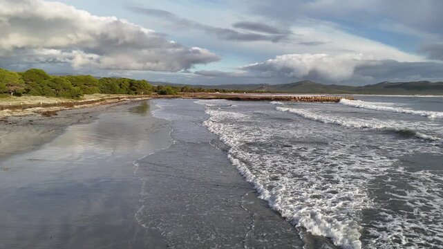 Aerial Drone View of Waves Crashing on a Curved Breakwater in Porto Pino, Sardinia, Italy