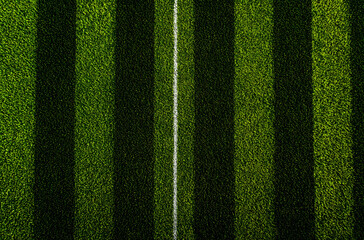Beautiful green grass texture with football field stripe pattern seen from top view, season for sport design, branding background, and editorial layout use