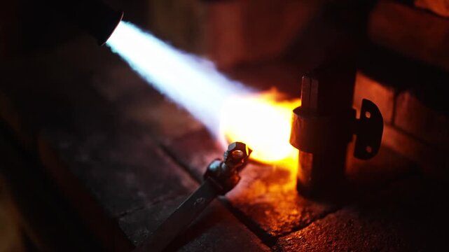 Professional jeweler melting precious metal with gas torch.