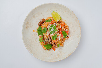 A vibrant dish of fried rice filled with vegetables, topped with cilantro and a slice of lime