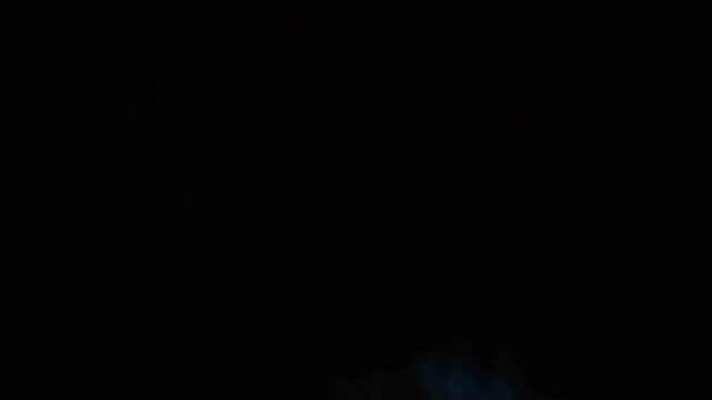 A powerful fire explosion starts with a blue flash from below, engulfing a granite stone in 1000fps slow motion. Intense combustion and flames fill the screen between mirrors. Concept: explosion blast