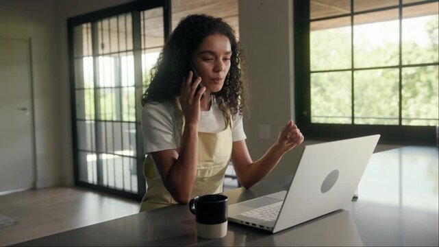 Woman in building interior, sitting at table with laptop and cell phone