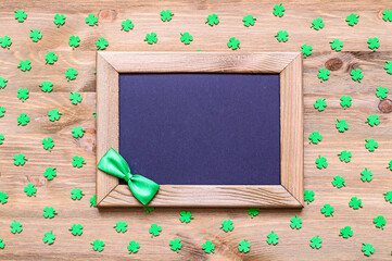 St Patricks Day background, wooden frame with green bow tie and free space for text and green quatrefoils on the natural wooden background