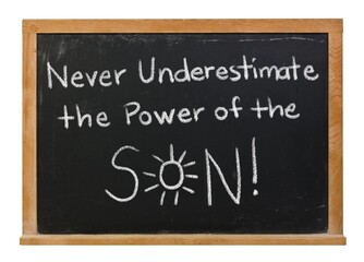 Obraz premium Never underestimate the power of the sun son handwritten in white chalk on a black chalkboard isolated in a wooden frame on white