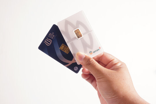 a man is holding 1 gram from antam gold and 3 gram from ubs gold on a isolated white background                        
