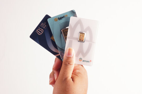 a man is holding 1 gram from antam gold, 3 gram from ubs gold and 5 gram from galeri24 on a isolated white background                        