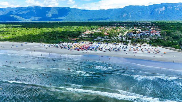 Vista a&eacute;rea da praia de Boraceia em Bertioga com faixa de areia extensa, mar azul e vegeta&ccedil;&atilde;o ao fundo, destacando o litoral norte de S&atilde;o Paulo e a ocupa&ccedil;&atilde;o urbana pr&oacute;xima ao mar