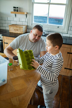 Father and son recycling in a home kitchen