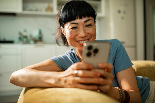 Smiling woman using smartphone at home