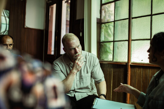 Attentive man listening during group therapy in community center
