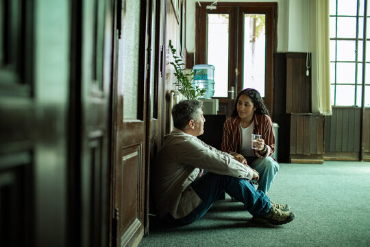 Two coworkers talking on the office hallway floor by a water cooler