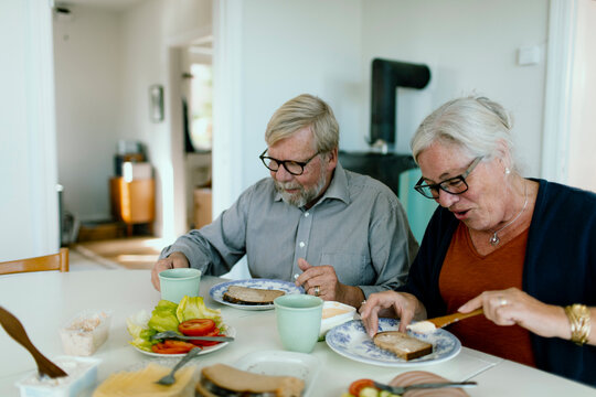 Senior couple preparing sandwiches in home kitchen
