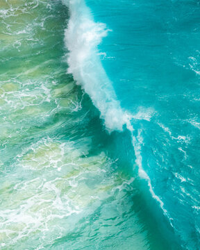 Aerial view of the ocean's turquoise waves crashing, creating a mesmerizing display of power and beauty, Bunga Mekar, Klungkung Regency, Bali, Indonesia.