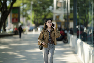 Obraz premium Smiling woman talking on phone walking in city