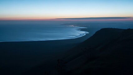 Fototapeta premium Twilight fades over a coastal town and the sea