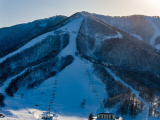 Winter landscape of snow-covered mountain with skiers on slopes in Japan