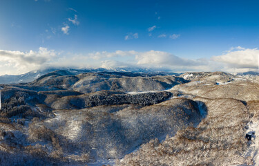 Sunny winter day landscape showing vast snowy hills and trees in Japan