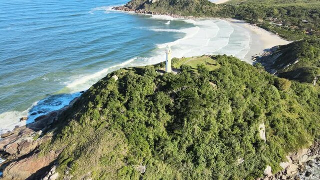 Voo sobre Ilha do Mel no litoral do Paran&aacute; em Parangu&aacute; com mar e c&eacute;u azul na praia de fora na mata atl&acirc;ntica mostrando o farol das conchas