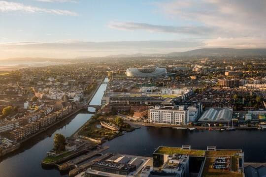 Aerial view of Aviva Stadium gleaming in the distance, juxtaposed against the calm waters and urban sprawl under a soft morning light, Dublin, County Dublin, Ireland.