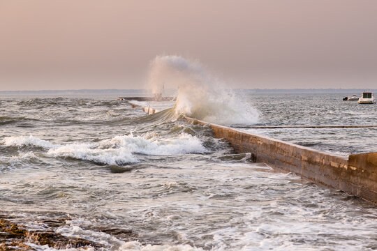 Temp&ecirc;te marine, vague d&eacute;ferlante sur le jet&eacute;e d'un petit port &agrave; la lumi&egrave;re rose d'un soir. Port de la Pointe St Gildas, Pr&eacute;failles