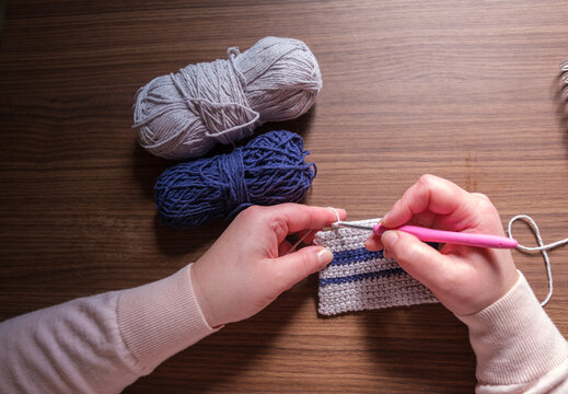 Person's Hands Working on a Crochet Project with a Pink Hook