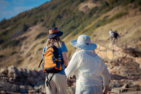 Hikers standing on rocky mountain trail resting and enjoying the scenic landscape during trekking adventure wearing backpacks and outdoor clothing representing hiking exploration and active lifestyle 