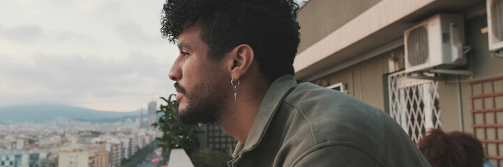 Obraz premium Close-up of young guy is standing on the balcony looking at the city. Panoramic